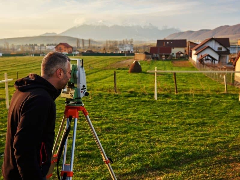 Land surveying work in progress as a surveyor measures a residential property to identify property boundaries
